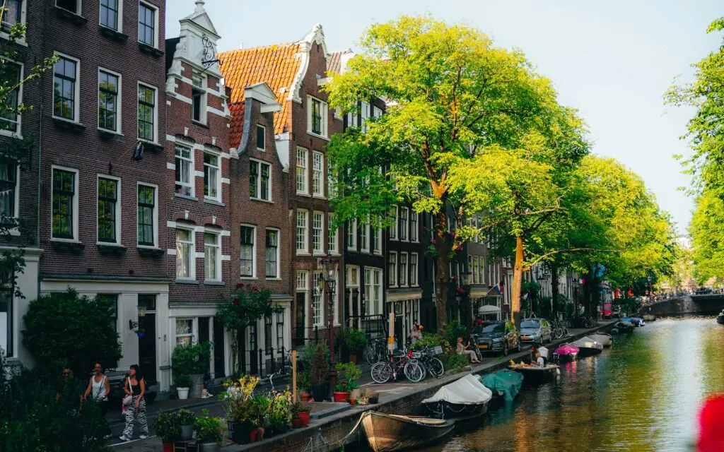 Gabled canal houses, bicycles, and boats along an Amsterdam canal in summer